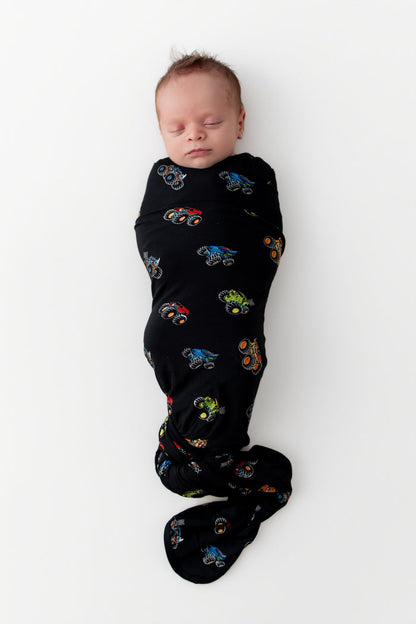 Baby sleeping in Black Swaddle Blanket in Monster Truck print on white background