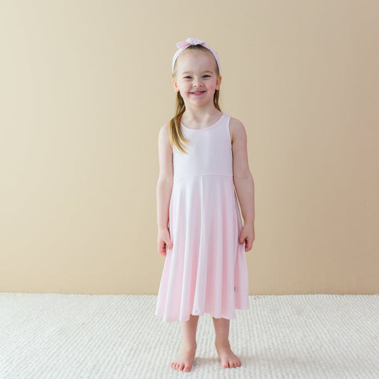 Child wearing Tank Twirl Dress in Sakura Pink with matching knotted bow