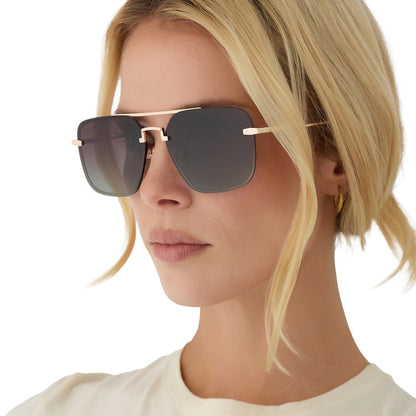 on model - blonde female wearing diff eyewear teddy oversized navigator sunglasses with a gold metal frame and brown gradient polarized lenses angled view