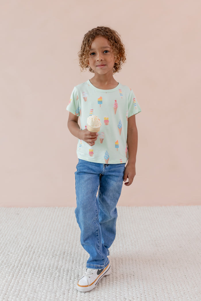 Child holding an ice cream cone wearing Toddler Basic Tee in Mint Ice Cream over Denim pants print on a beige background