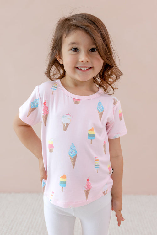 Child wearing Toddler Basic Tee in Sakura Ice Cream print over white leggings on a beige background