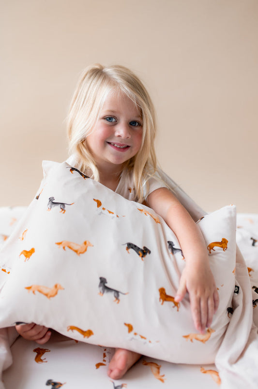 Girl sitting with a Beige Toddler pillowcase in Dachshund print