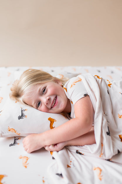 Girl lying under a Beige Toddler Blanket in Dachshund print over a similar print Toddler pillowcase