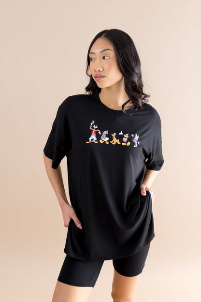 Woman wearing a black t-shirt with colorful mickey mouse graphic design on a beige background