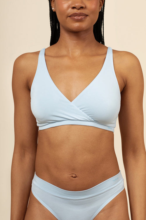 Woman wearing a light blue bra set against a beige background
