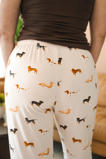 Model showcasing the back of beige Women's Lounge Pants in Dachshund print under a brown camisole