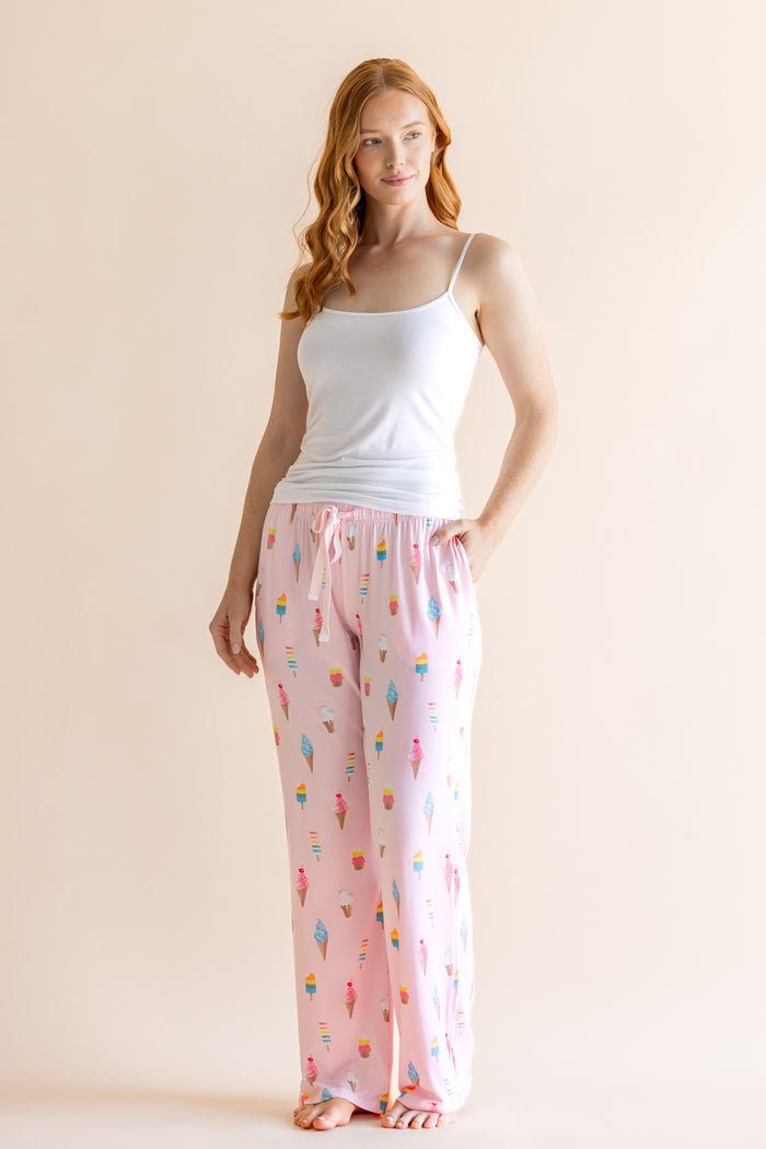 Model wearing Pink Women's Lounge Pants in Ice Cream print under white camisole on beige background