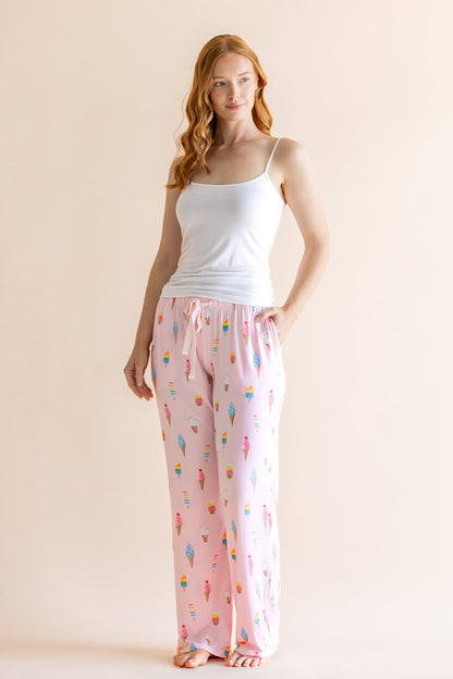 Model wearing Pink Women's Lounge Pants in Ice Cream print under white camisole on beige background