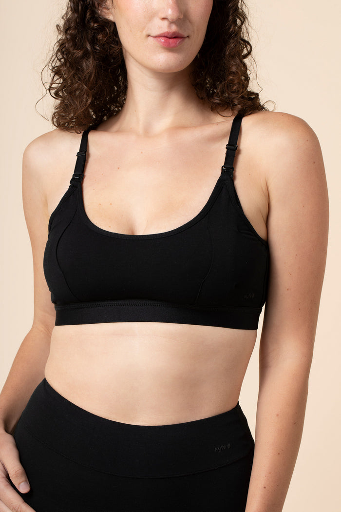 Woman wearing a black pumping bra and leggings on a beige background
