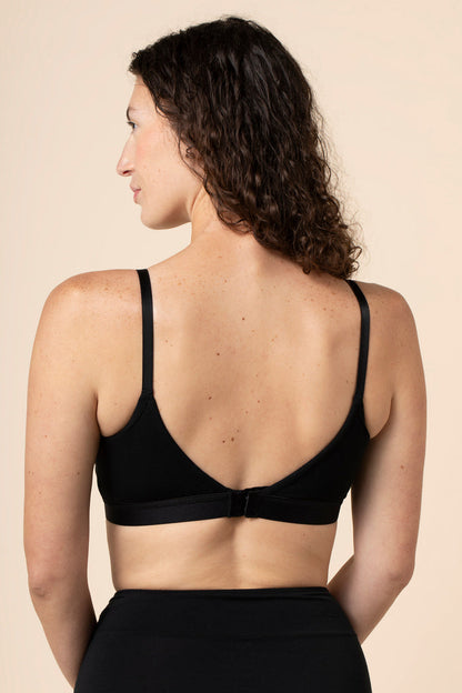 Woman wearing a black nursing/pumping bra against a beige background