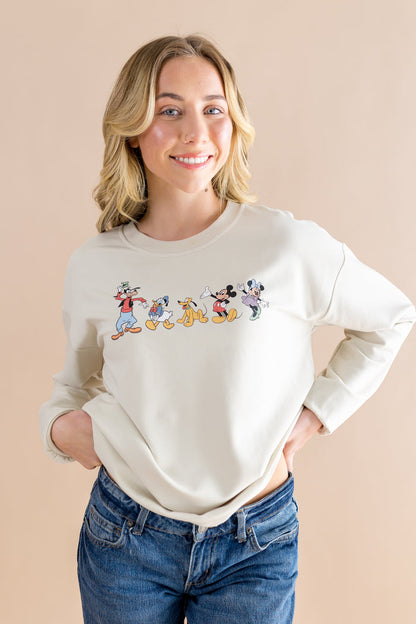 Woman wearing a cream sweatshirt with cartoon character design on a beige background