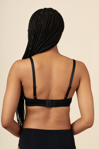 Person wearing a black bralette on a beige background