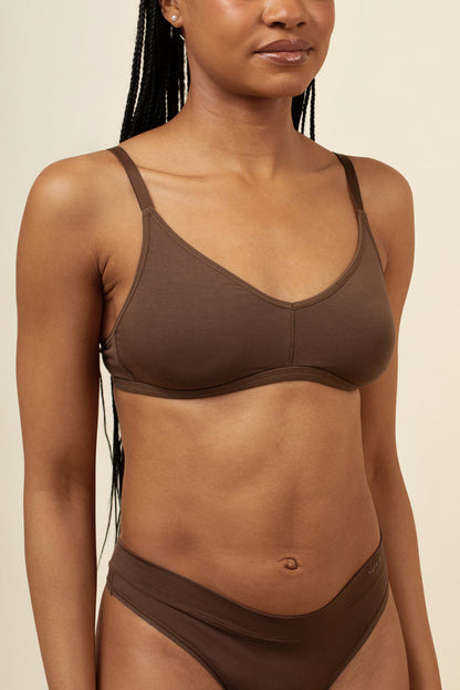 Woman wearing a brown bra set against a beige background