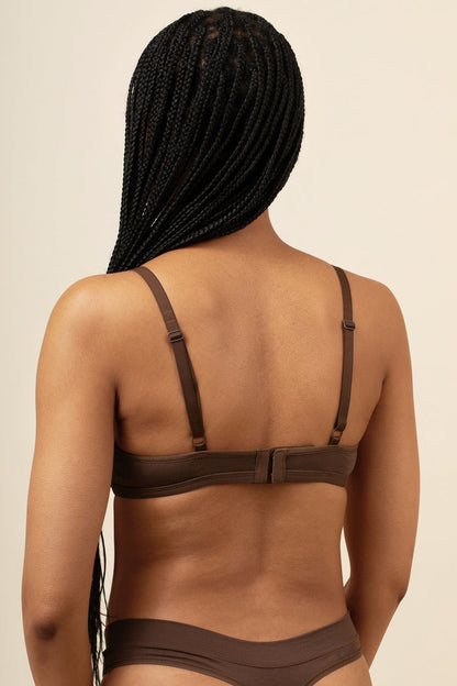 Brown bra and panties set worn by a person with braided hair on a beige background