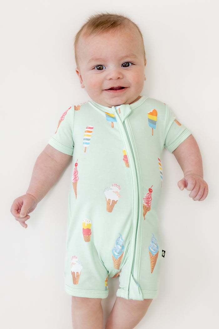 Baby smiling in zippered shortall romper with Mint Ice cream print on a beige background
