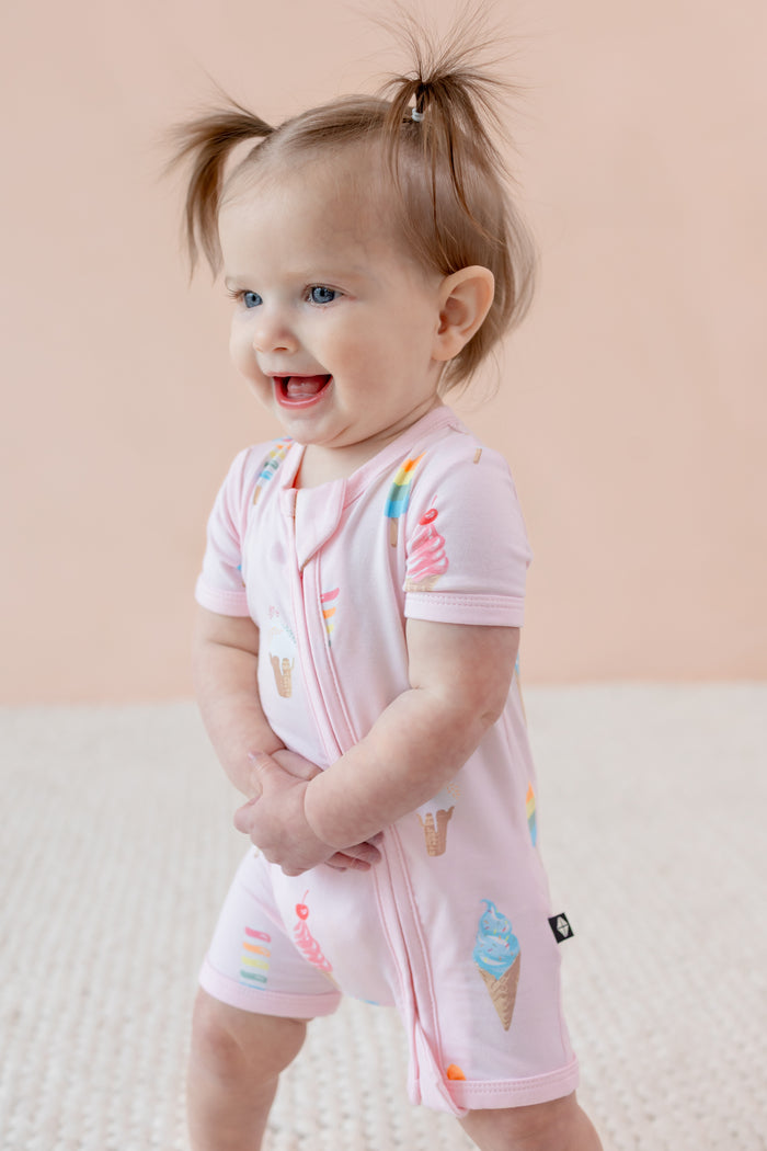 Child in Zippered shortall romper in Sakura Ice cream print on a beige background