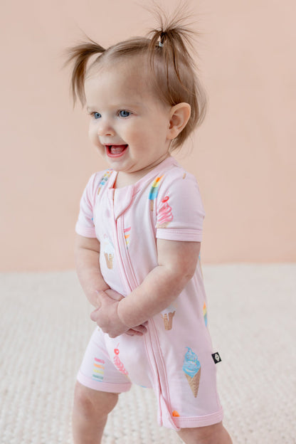 Child in Zippered shortall romper in Sakura Ice cream print on a beige background