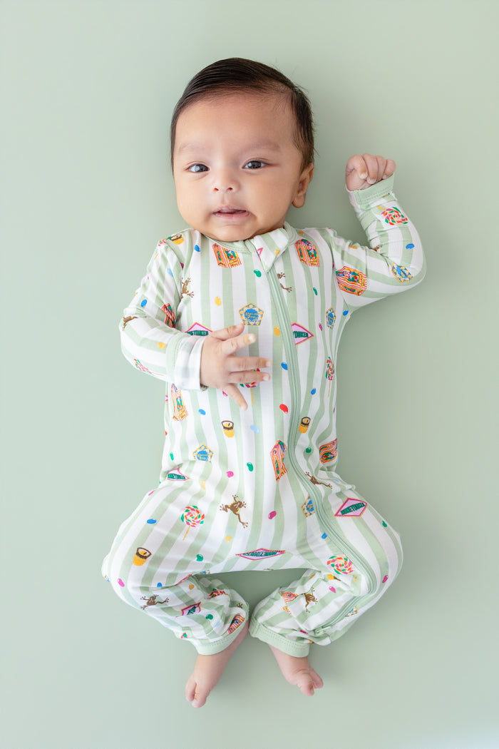 Baby wearing a green and white striped zippered romper with colorful Harry Potter patterns on a green background