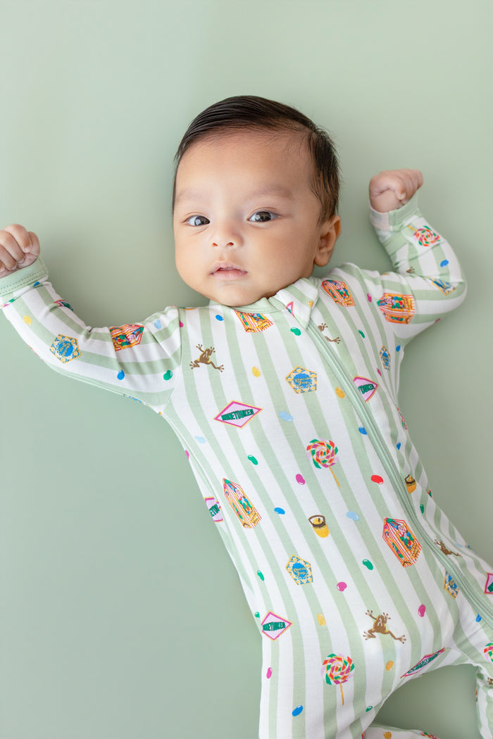 Baby in a green and white striped zippered romper with colorful Harry Potter patterns on a green background