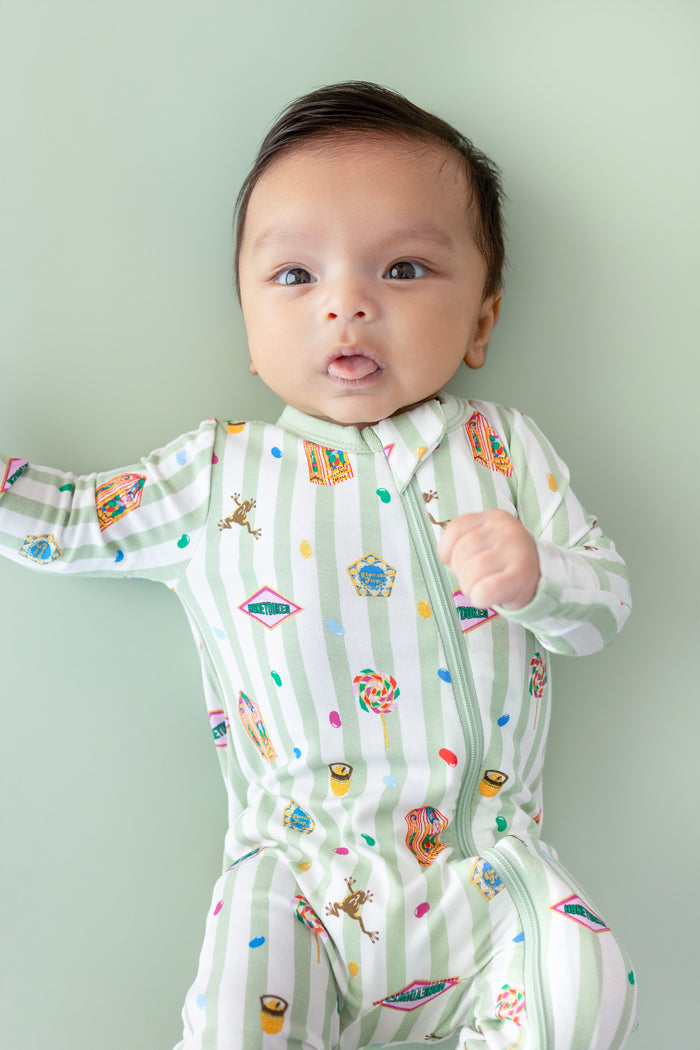 Baby in a green and white striped zippered romper with colorful Harry Potter patterns on a green background