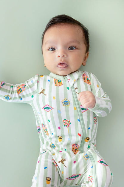 Baby in a green and white striped zippered romper with colorful Harry Potter patterns on a green background