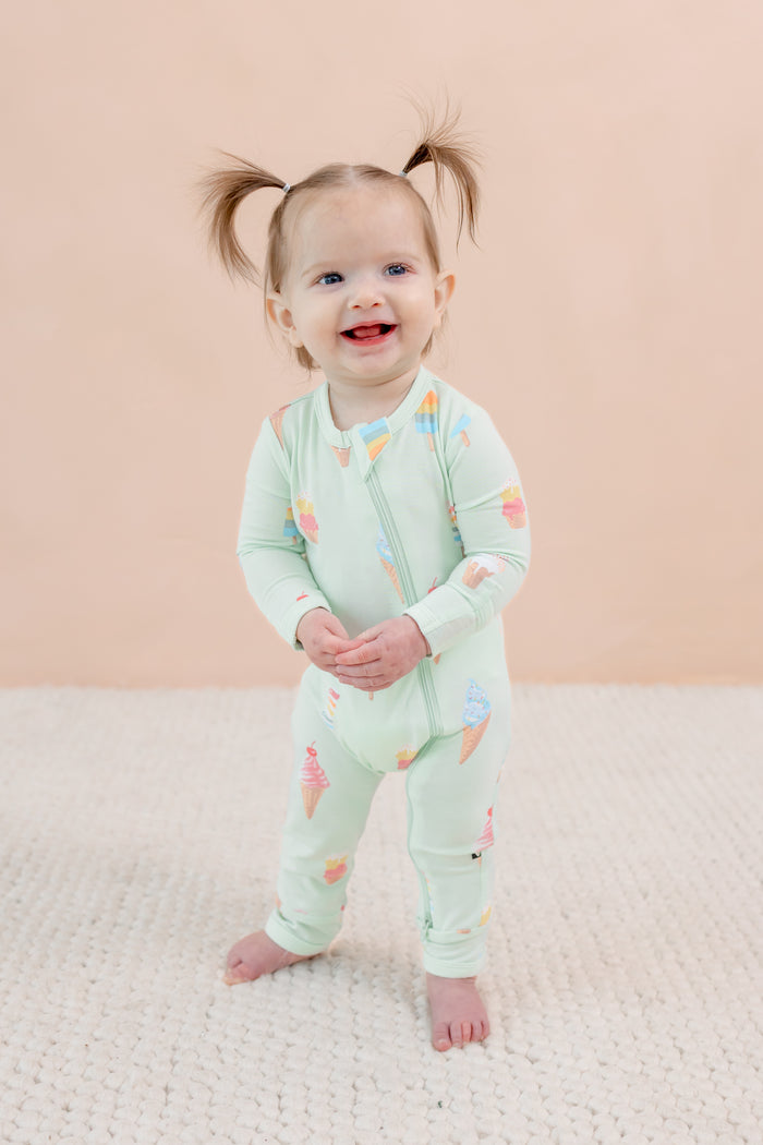 Child wearing a light green outfit with colorful ice cream patterns on a beige background
