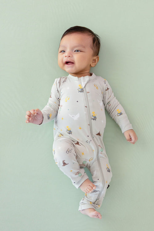 Baby wearing a Harry Potter patterned Zippered Romper on a green background