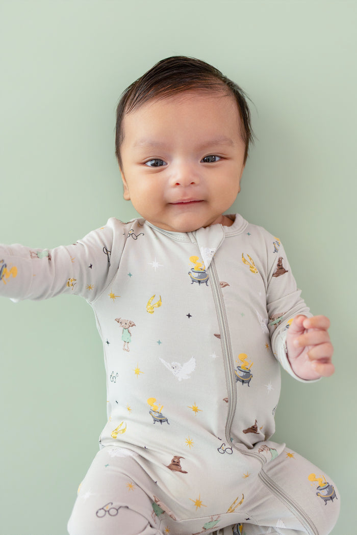 Baby wearing a Harry Potter patterned Zippered Romper on a green background
