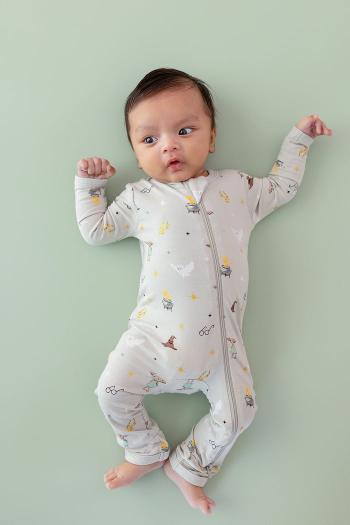 Baby wearing a Harry Potter patterned Zippered Romper on a green background